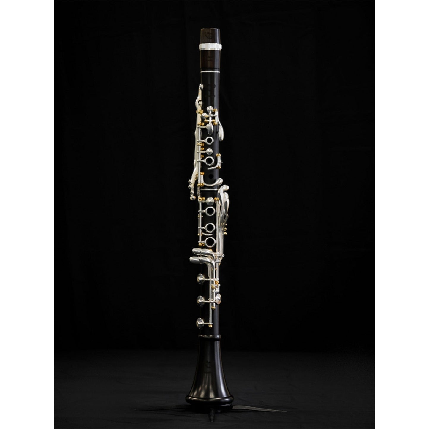 full length shot of the Royal Global Firebird clarinet assembled on a clarinet stand, against a black background