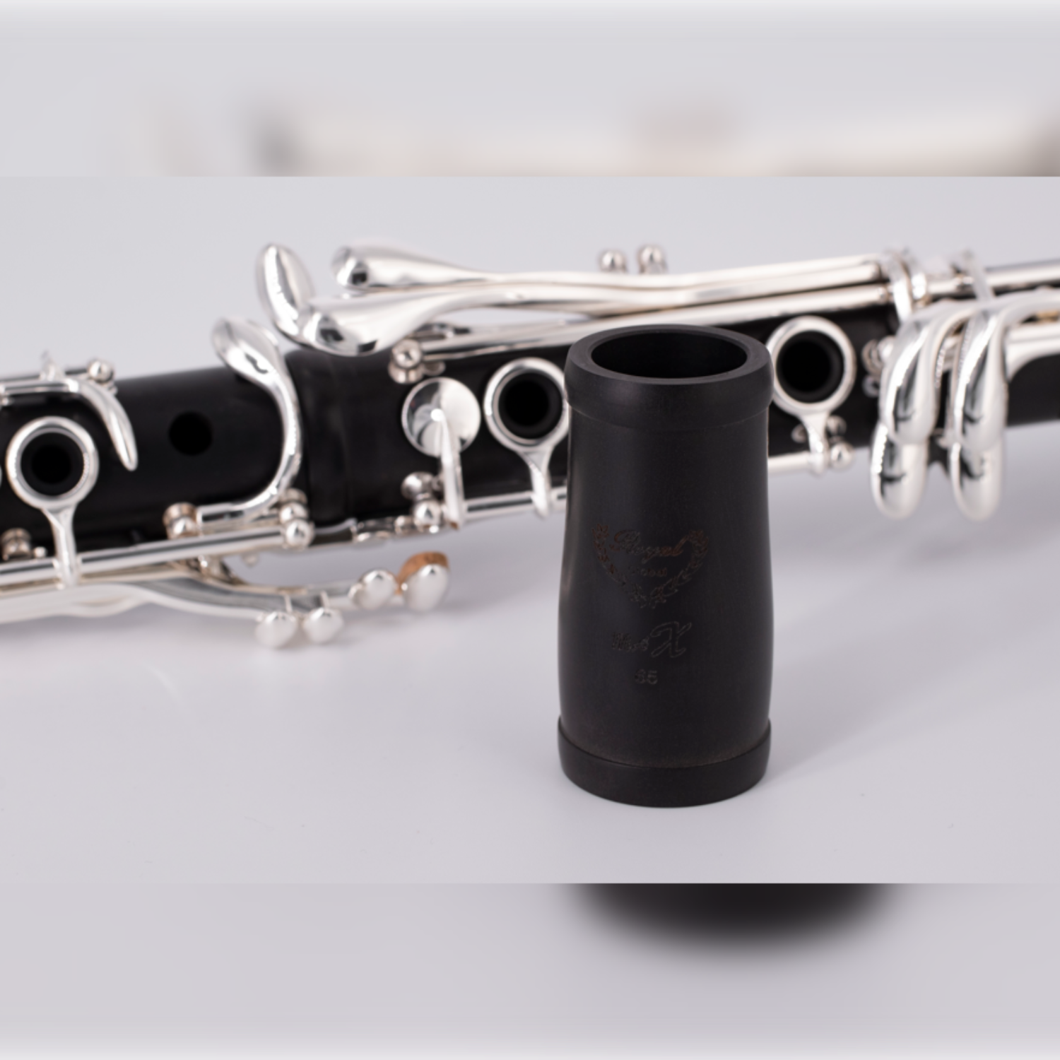 barrel of Royal Global Max Bb clarinet sitting in front of assembled upper and lower joint, closeup of logo engraving