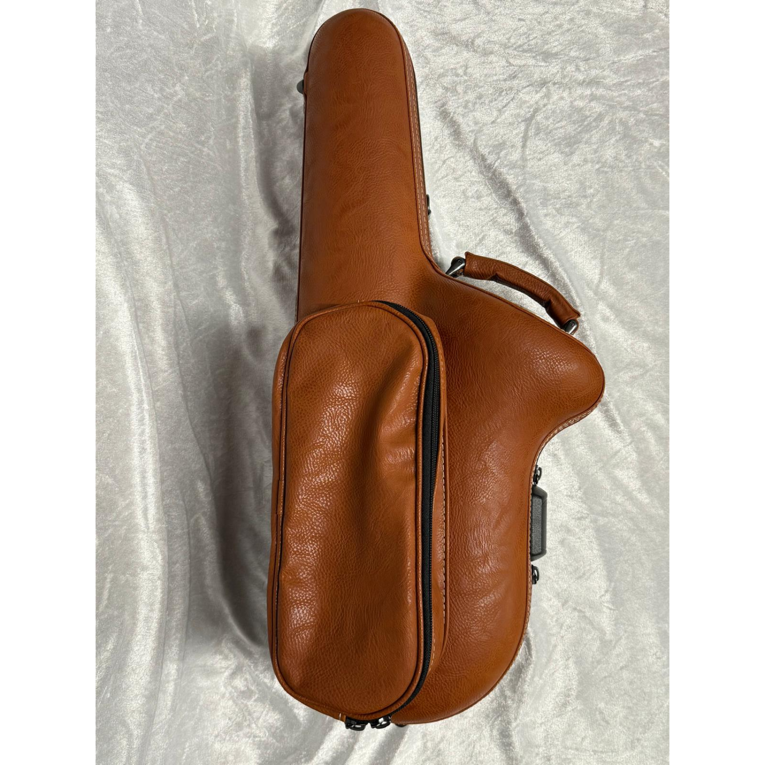 brown leather case, closed, showing external accessory pouch, on white velvet background